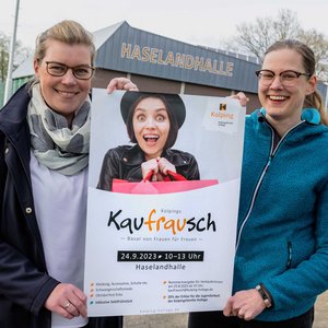 Martina Unland und Janina Bode zeigen das Plakat zu „Kolpings Kaufrausch“.