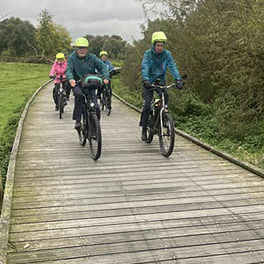 Radfahrer fahren über einen Holzsteg.