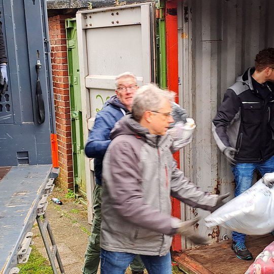 Ehrenamtliche Helfer verladen die gesammelten Altkleider auf einen Lkw.